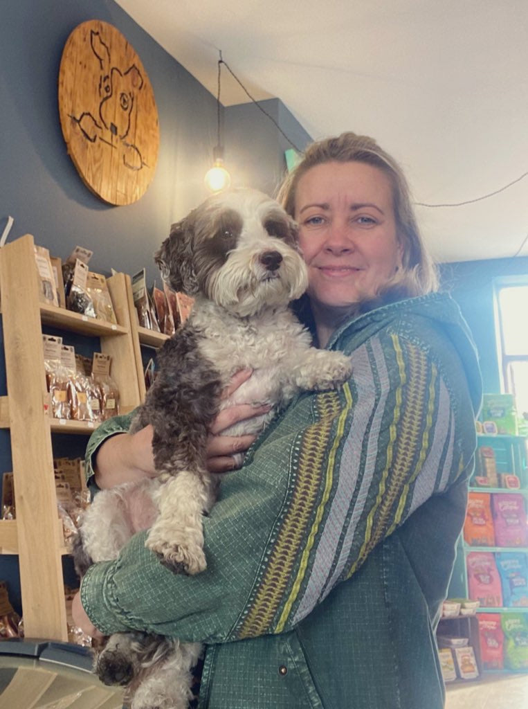 Woman holding a dog in a store with shelves and decor in the background