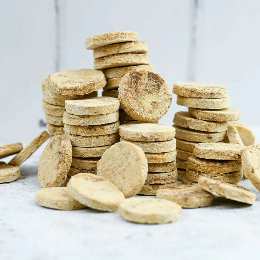 Stacks of round, brown cookies on a light gray surface with a neutral background